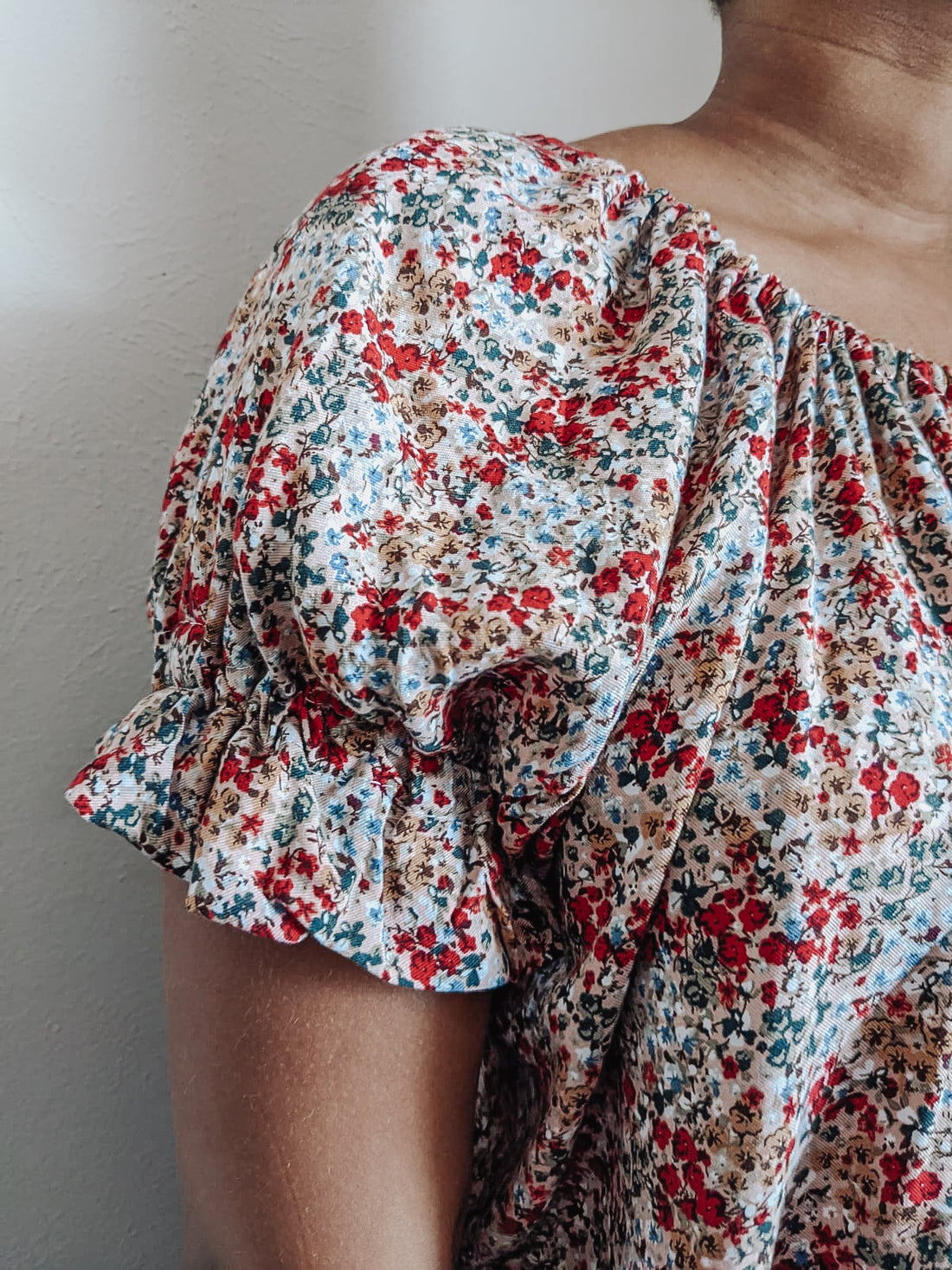 close up photo of a floral blouse with a ruffle sleeve and drawstring neckline